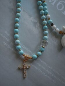 Close-up of a turquoise beaded necklace with a cross pendant, exuding elegance.
